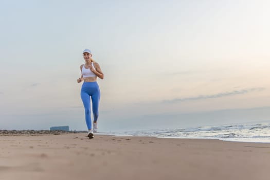 Beautiful sportive woman running along beautiful sandy beach, healthy lifestyle, enjoying active summer vacation near the sea. High quality photo