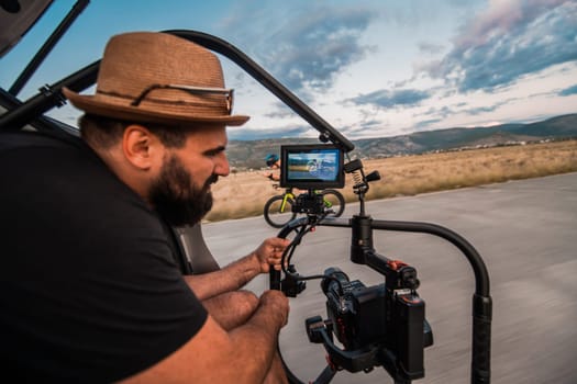 A videographer recording a triathlete riding his bike preparing for an upcoming marathon.Athlete's physical endurance and the dedication required to succeed in the sport