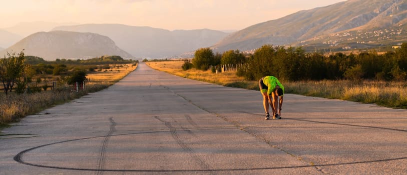 In the early morning light, the triathlete preparing for run by tying his shoes. With focused determination and unwavering dedication, he readies himself for the physical and mental challenge ahead, striving to push his limits and achieve his goals