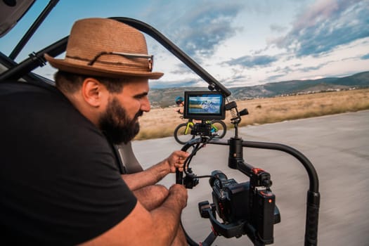 A videographer recording a triathlete riding his bike preparing for an upcoming marathon.Athlete's physical endurance and the dedication required to succeed in the sport