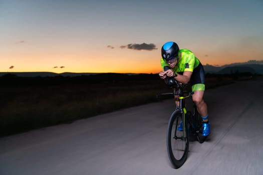 A triathlete rides his bike in the darkness of night, pushing himself to prepare for a marathon. The contrast between the darkness and the light of his bike creates a sense of drama and highlights the athlete's determination and perseverance