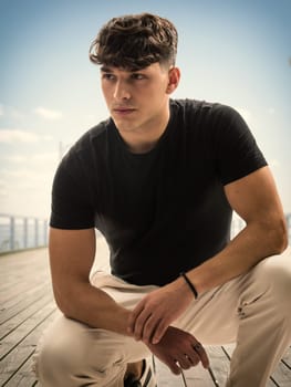 A young man sitting on a wooden deck