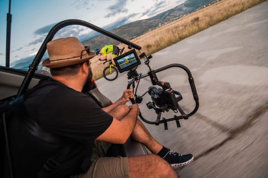 A videographer recording a triathlete riding his bike preparing for an upcoming marathon.Athlete's physical endurance and the dedication required to succeed in the sport