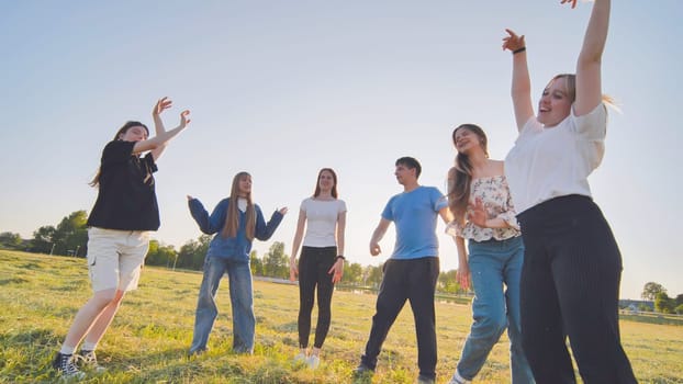 Funny jolly friends dancing in the city meadow in the evening