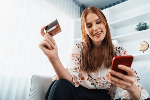 Young happy woman buy product by online shopping at home while ordering items from the internet with credit card online payment system protected by utmost cyber security from online store platform