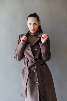 fashionable woman in a raincoat on a gray background