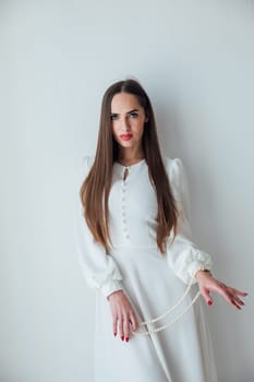 brunette woman standing on white background with beads