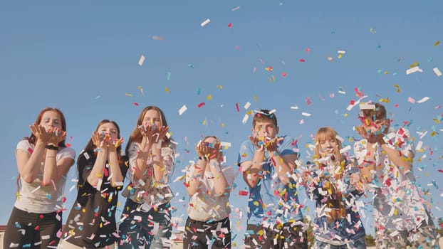 Friends blow colorful paper confetti on a sunny day