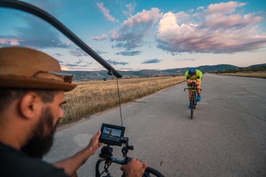 A videographer recording a triathlete riding his bike preparing for an upcoming marathon.Athlete's physical endurance and the dedication required to succeed in the sport