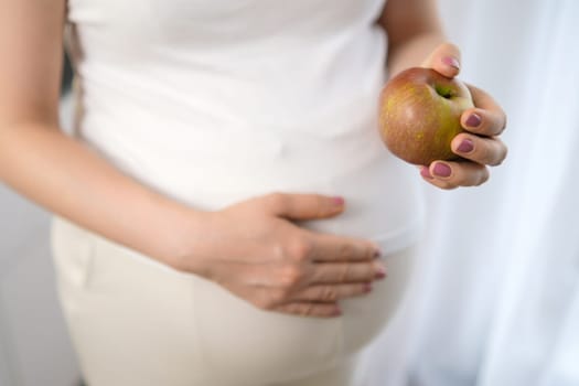 Close up apple in pregnant womans hand. Diet, fruits and vitamins during pregnancy.
