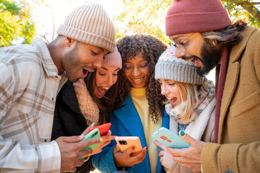 Group of young friends using cell phones surprised expression outdoors. High quality photo