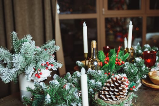 Festive table setting among winter decorations and white candles. Top view, flat lay. The concept of a Christmas or Thanksgiving family dinner.