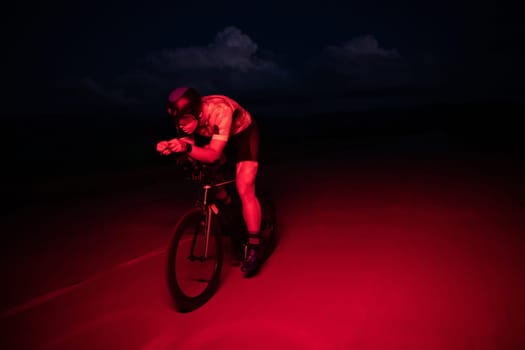 A triathlete rides his bike in the darkness of night, pushing himself to prepare for a marathon. The contrast between the darkness and the light of his bike creates a sense of drama and highlights the athlete's determination and perseverance