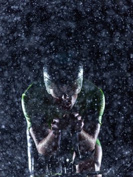 A triathlete braving the rain as he cycles through the night, preparing himself for the upcoming marathon. The blurred raindrops in the foreground and the dark, moody atmosphere in the background add to the sense of determination and grit shown by the athlete