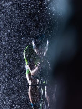 A triathlete braving the rain as he cycles through the night, preparing himself for the upcoming marathon. The blurred raindrops in the foreground and the dark, moody atmosphere in the background add to the sense of determination and grit shown by the athlete