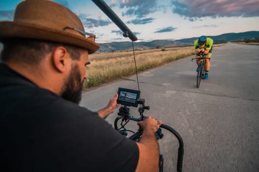 A videographer recording a triathlete riding his bike preparing for an upcoming marathon.Athlete's physical endurance and the dedication required to succeed in the sport