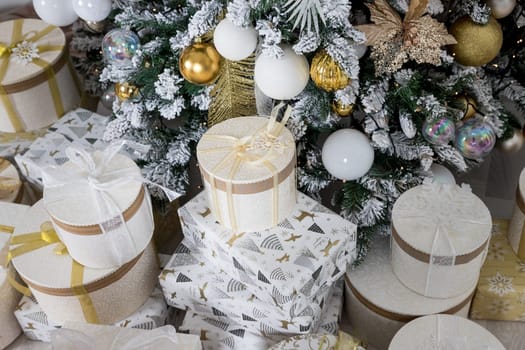 Photo of luxury gift boxes under Christmas tree, New Year home decorations, golden wrapping of Santa presents