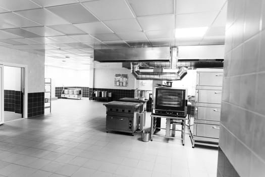 Industrial kitchen in school restaurant with professional equipment and pans