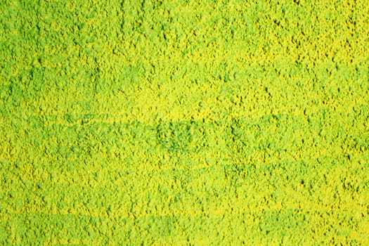 Texture of a wall covered with yellow and green paint, damaged by time. Rough surface of an old painted concrete wall.