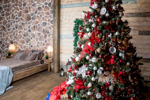 Christmas, New Year loft interior with large window, black wall background, garlands, fir tree with lamps and Christmas gifts, bed with checkered plaid