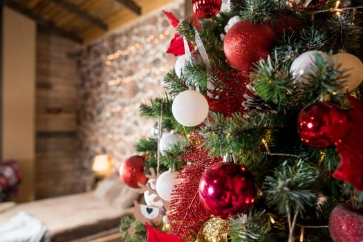 Magic glowing tree. Christmas home interior with Christmas tree. Red and white balls hanging on pine branches. Festive lights in the brick wall background.