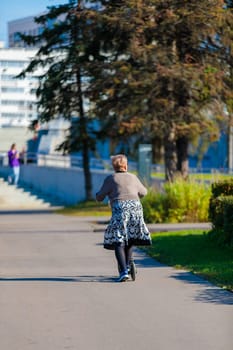 A grown woman rides a scooter in the park. Healthy lifestyle