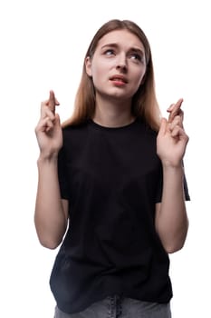 Portrait of a teenage girl in a black T-shirt with fingers crossed.