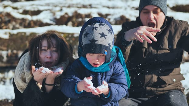A young, happy family blowing in the snow on a winter's day