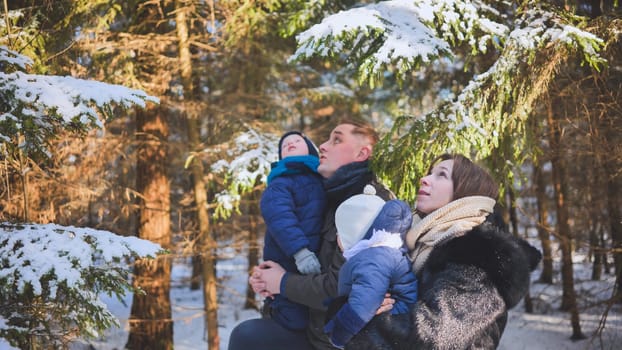 A happy family looks at the trees in the winter woods