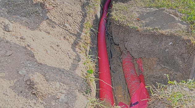 Cables in the trench. High-voltage cables in a protective covering in an excavation. Concept of electrical installations, construction works, building renovations and building refurbishments.