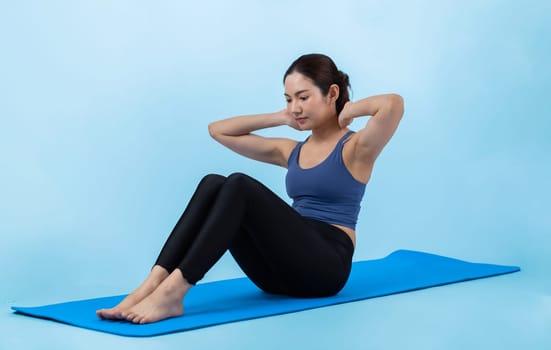 Asian woman in sportswear doing crunch on exercising mat as workout training routine. Attractive girl in pursuit of healthy lifestyle and fit body physique. Studio shot isolated background. Vigorous