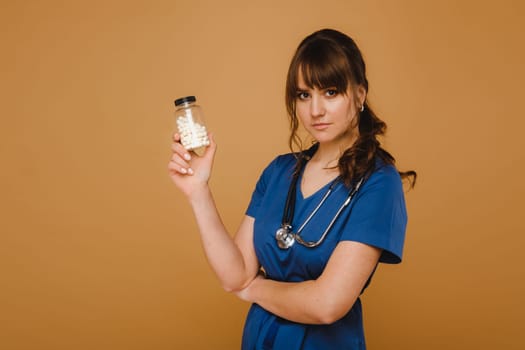 white pills in a jar of a female doctor. The doctor shows the vitamin capsules.Medicinal capsules