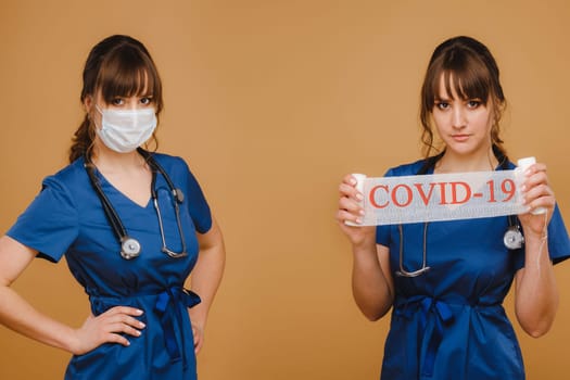 a doctor in a mask, gloves and with a stethoscope holds the inscription covid-19 and a pediatrician.