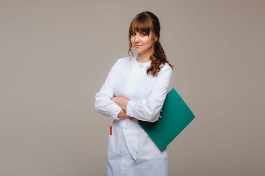 Portrait of a female medical worker in a gray background with a medical report.Girl doctor with a Notepad.