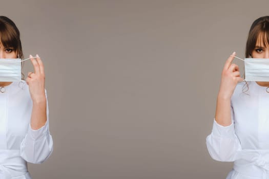 A girl doctor stands in a medical mask, isolated on a gray background