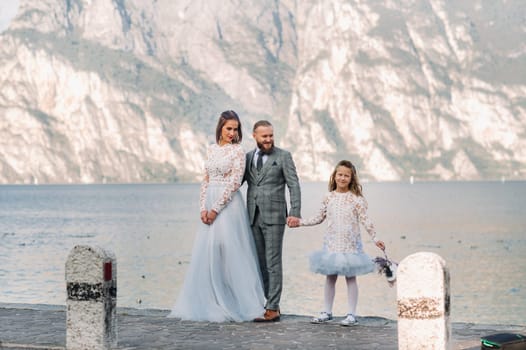Italy, Lake Garda. Beautiful family on the shores of lake Garda in Italy at the foot of the Alps. Father, mother and daughter in Italy.