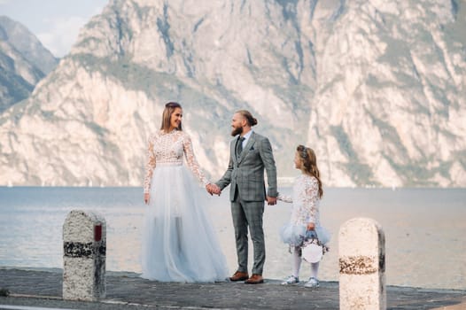 Italy, Lake Garda. Beautiful family on the shores of lake Garda in Italy at the foot of the Alps. Father, mother and daughter in Italy.