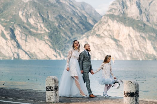 Italy, Lake Garda. Beautiful family on the shores of lake Garda in Italy at the foot of the Alps. Father, mother and daughter in Italy.