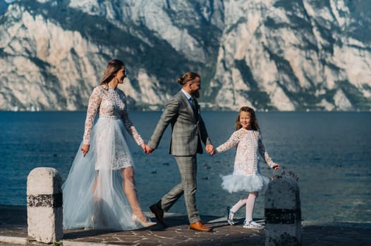 Italy, Lake Garda. Beautiful family on the shores of lake Garda in Italy at the foot of the Alps. Father, mother and daughter in Italy.