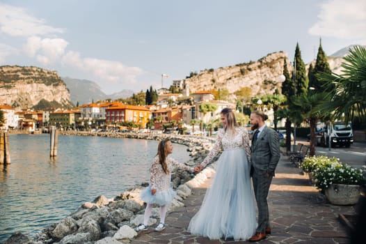 Italy, Lake Garda. Beautiful family on the shores of lake Garda in Italy at the foot of the Alps. Father, mother and daughter in Italy.