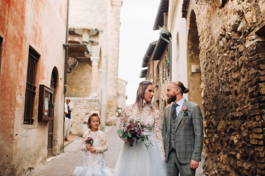 A happy young family walks through the old town of Sirmione in Italy.Stylish family in Italy on a walk.