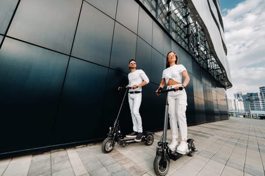 A couple on electric scooters ride around the city, a couple in love on scooters.