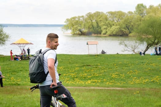 A cyclist with a backpack is standing on a bicycle in a clearing enjoying nature.