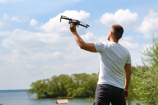 A man with a flying vehicle in his hands, raised to the sky in nature.Launching a drone.