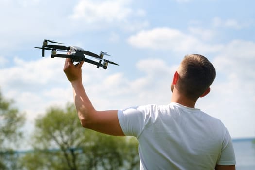 A man with a flying vehicle in his hands, raised to the sky in nature.Launching a drone.