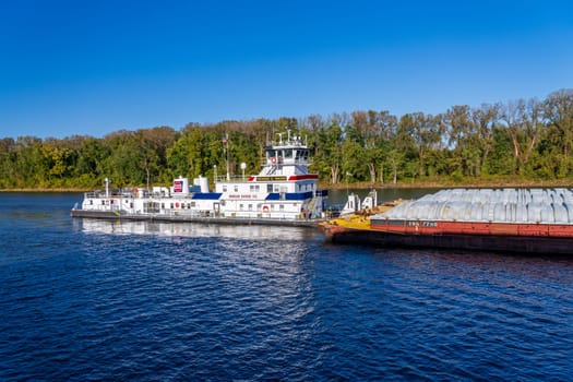 Hannibal, MO - 20 October 2023: Ingram Barge Co pusher tugboat pushing rows of barges with grain down the Upper Mississippi river