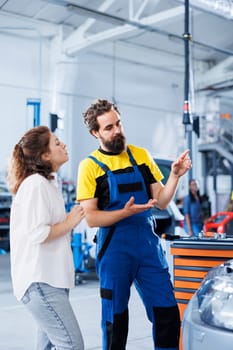 Expert in repair shop using AR technology to show customer car maintenance parameters. Garage worker using futuristic vr headset to inform client of what problems her vehicle is facing