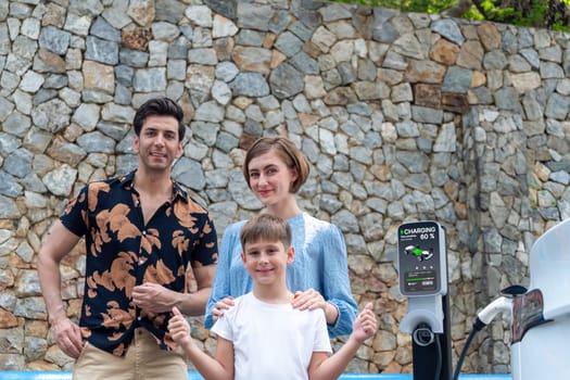 Family road trip vacation with electric vehicle, lovely family recharge EV car with green and clean energy. Stone seawall background and eco friendly car travel for sustainable environment. Perpetual