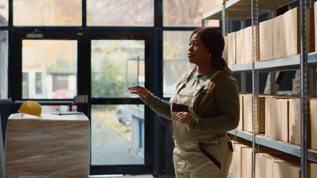 Employee in warehouse using AR holographic technology to visualize how to best stack merchandise on shelves to make room for more. Worker in storage establishment uses augmented reality