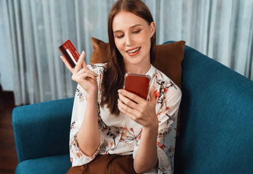 Young happy woman buy product by online shopping at home while ordering items from the internet with credit card online payment system protected by utmost cyber security from online store platform